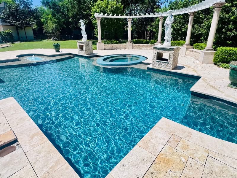 Clear blue pool with a raised spa and white pergola